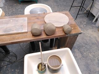 Three balls of clay in front of a pottery wheel.
